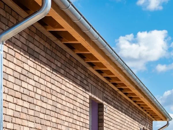 Canalón metálico y bajante instalados bajo el alero de una vivienda